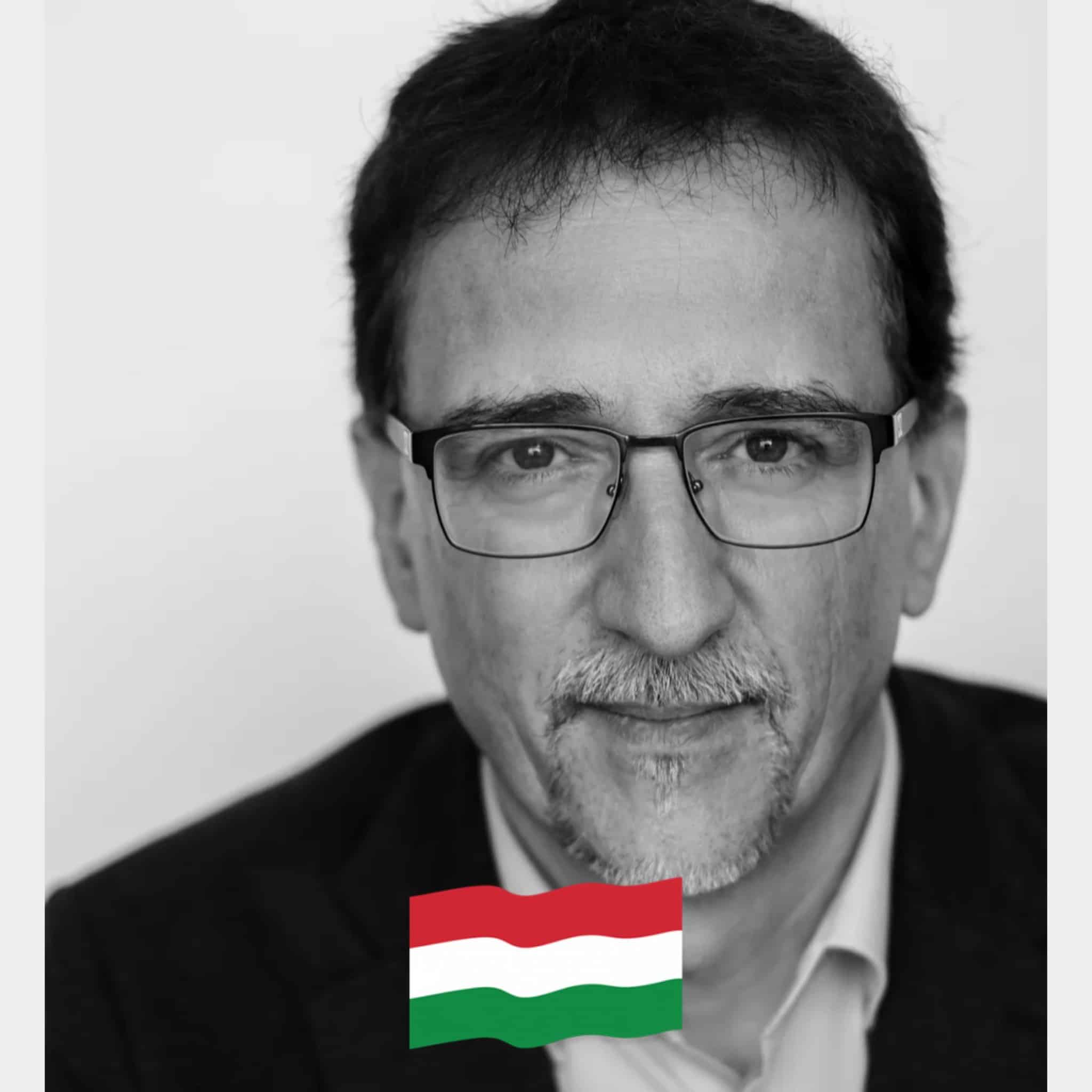 Minta fekete-fehér portré férfi, szemüveg, magyar zászlóval a kép alján.