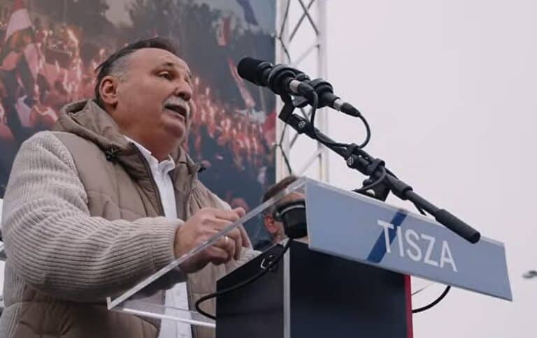 2019 magyar politikus beszédet tart nyilvános eseményen, mikrofon és hangfal előtt.