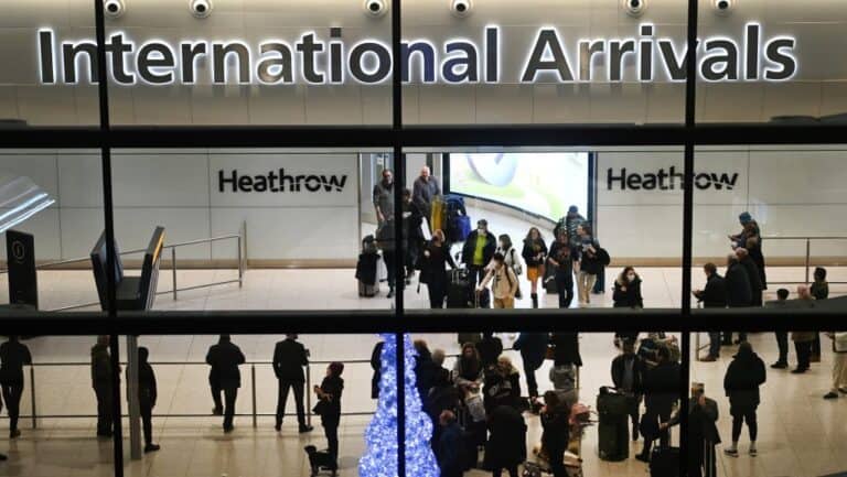 International arrivals at Heathrow Airport, many travelers with luggage returning home.