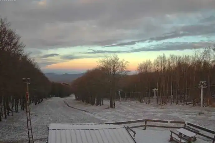 Csúszós útszakasz havas tájon, naplemente a háttérben, téli időjárás Magyarországon.