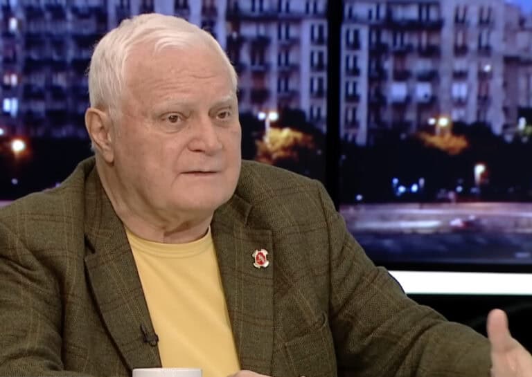 Idős férfi interjú a MagyarNewsOnline műsorában, városi háttérrel az este sötétedésében.