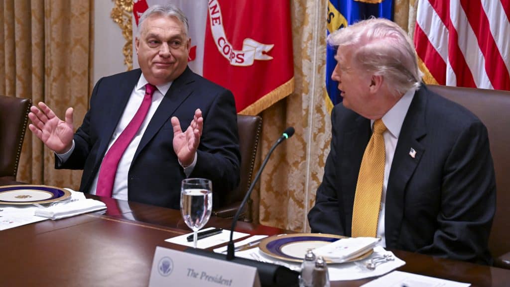 Gazdag politikai megbeszélés két vezető között az asztalnál, háttérben nemzeti zászlók.