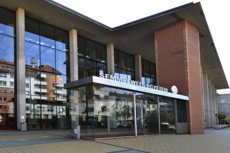 Szechenyi egyetem modern épülete, üvegfalak, a napfényben tükröződő városházi épületek.