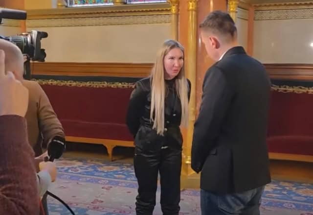 The woman and man having an interview in a historic hall.