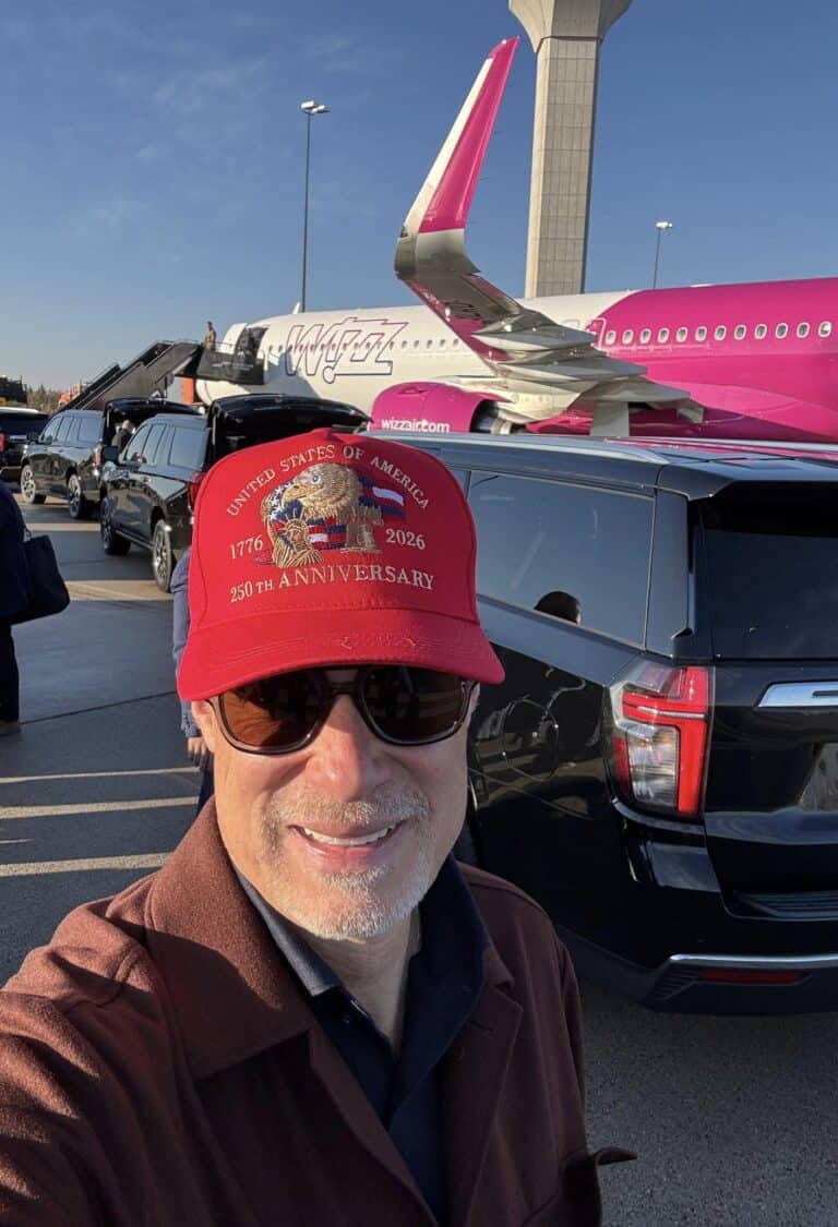 Repülőtérépítmény és egyember fotója repülővel a háttérben, napsütéses időben.