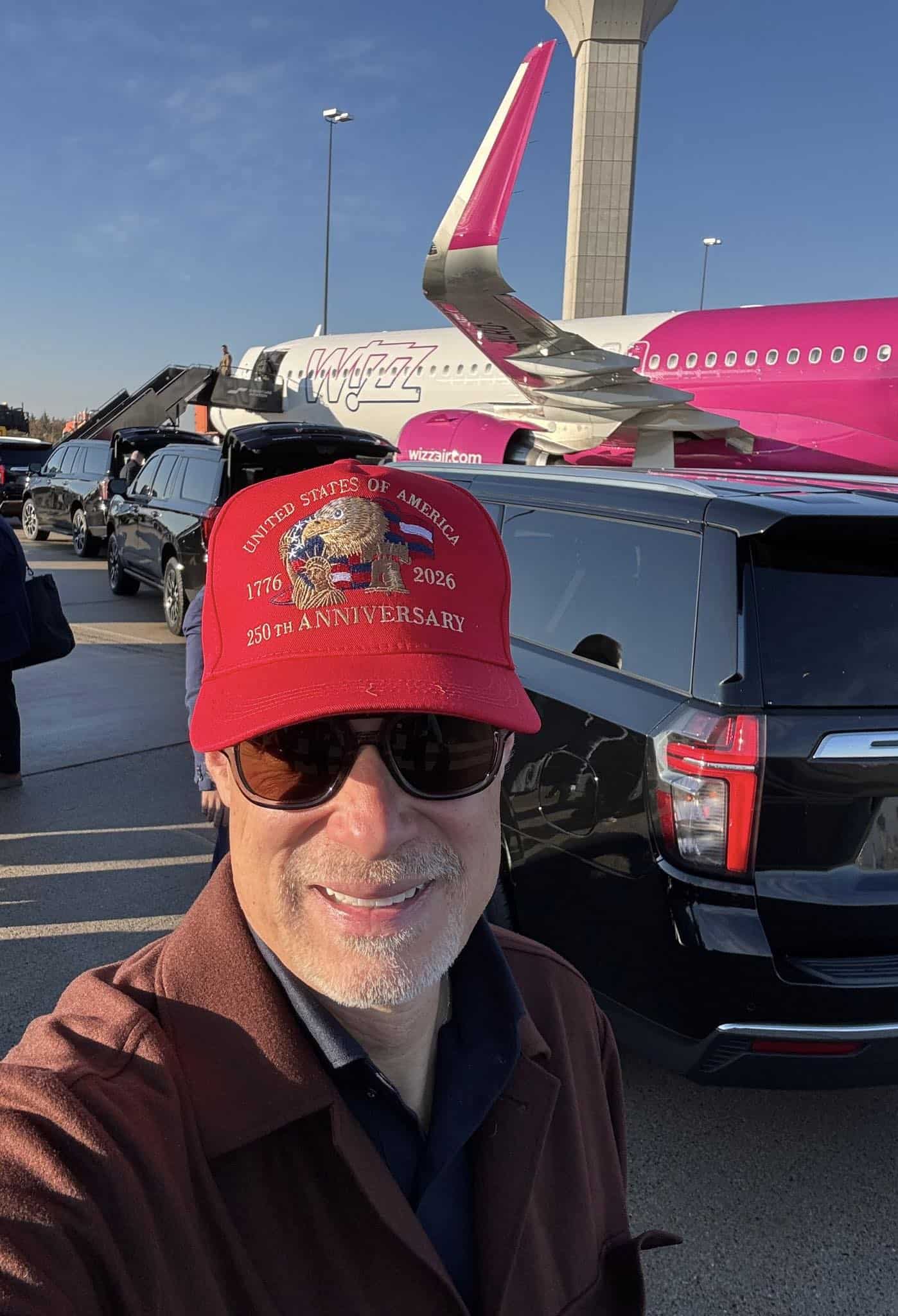 Repülőtérépítmény és egyember fotója repülővel a háttérben, napsütéses időben.