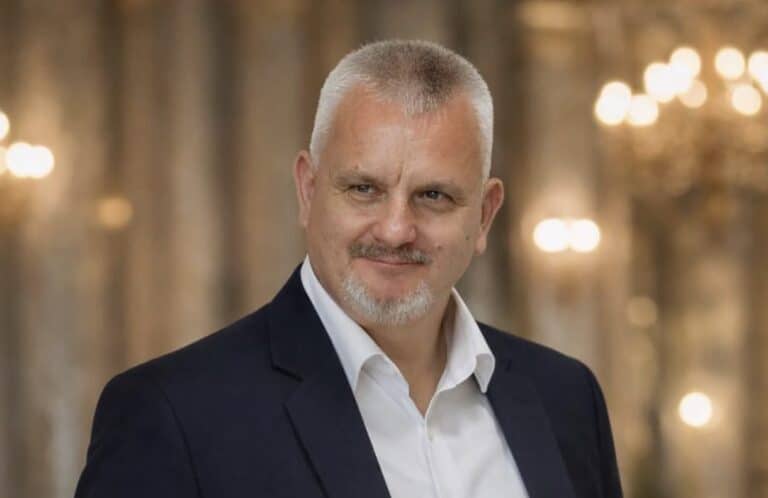 Férfi portré egy elegáns háttérrel, hivatalos megjelenésben.