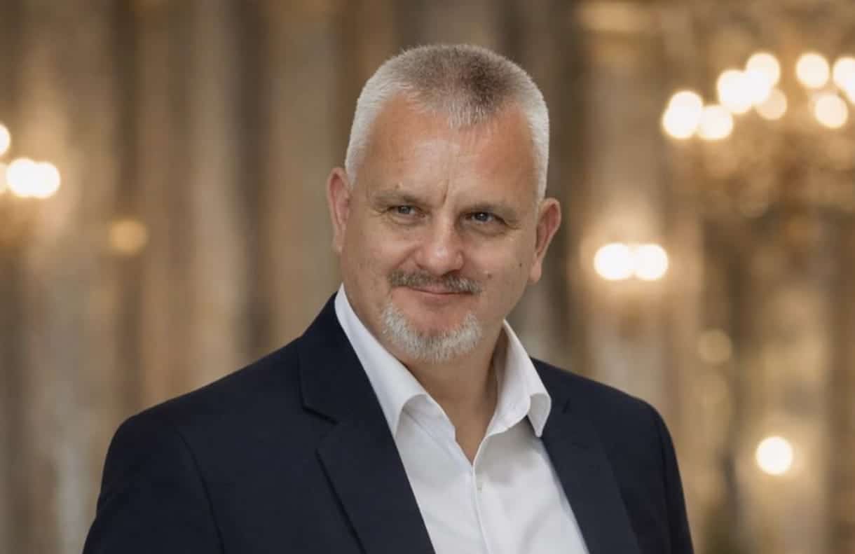 Férfi portré egy elegáns háttérrel, hivatalos megjelenésben.