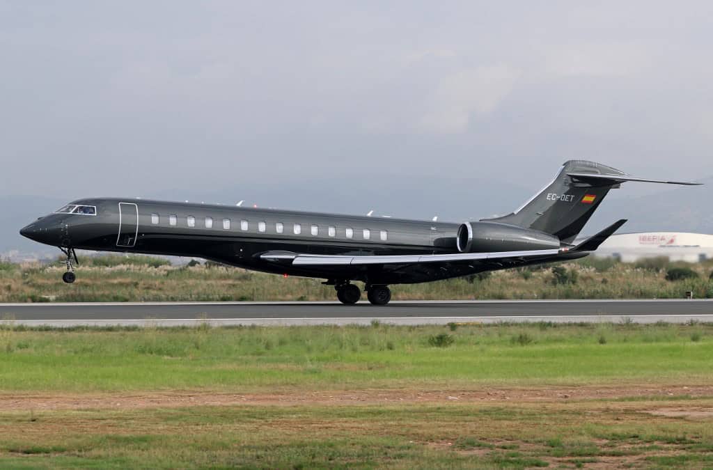 Luxus magánjet - fekete repülőgép a leszállópályán, felhős ég alatt.