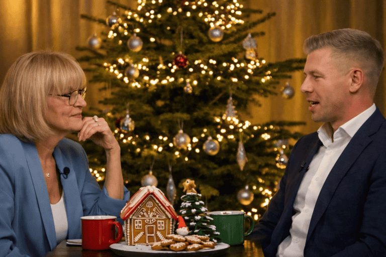 Boldog karácsonyi beszélgetés two people sitting at table in front of decorated Christmas tree.
