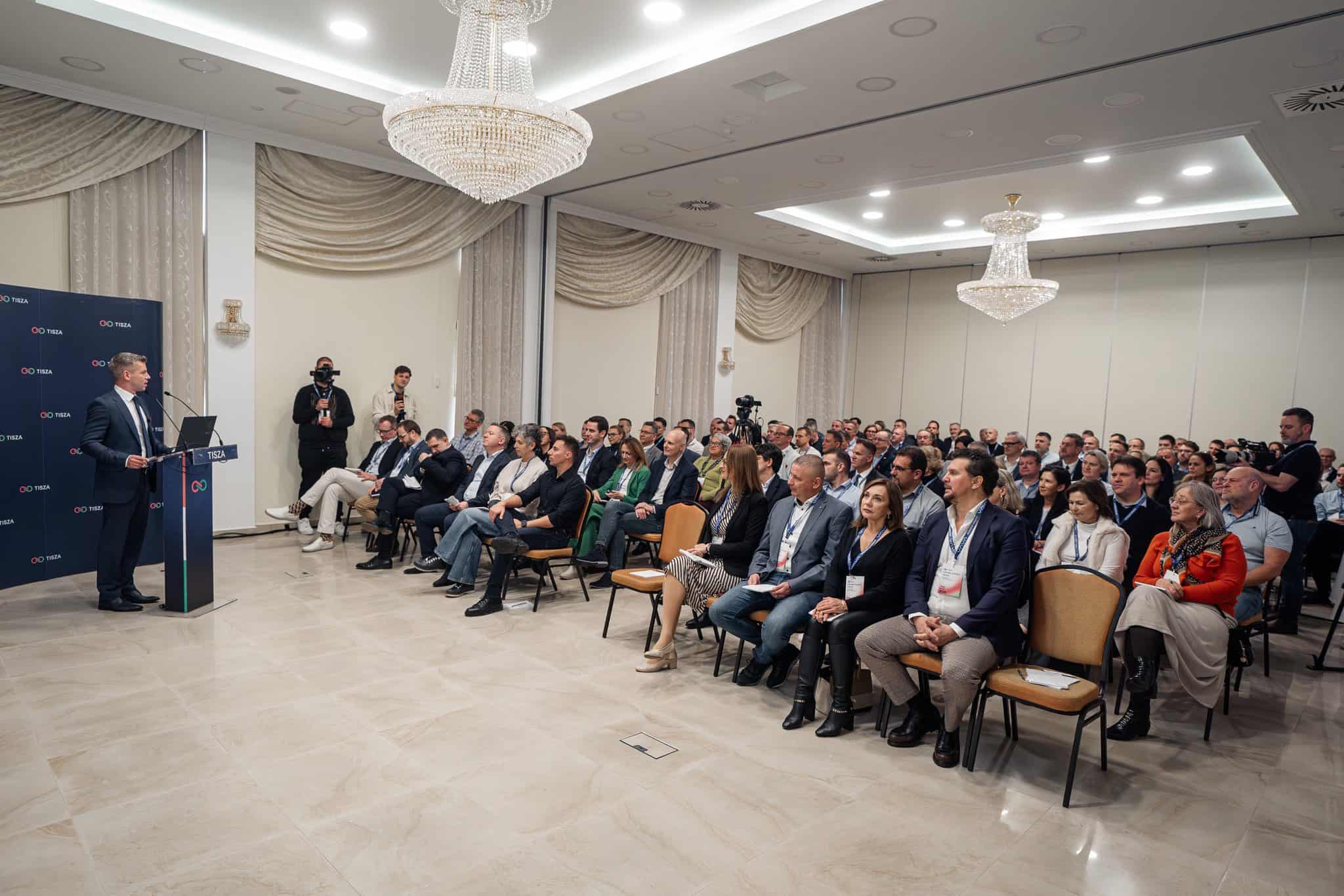 Csapatépítő esemény magyar üzleti konferencia, ahol hallgatóság figyel egy előadót.