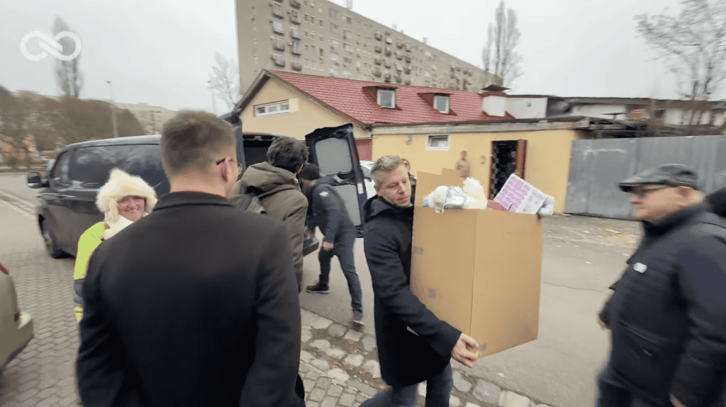 Szociális segélyszállítók láthatók magyarországi utcán, segíteni próbáló önkéntesek.