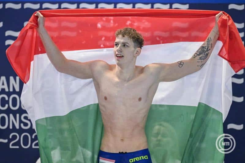 Atlétika olimpiai bajnok magyar úszó ünnepel az olimpián, magyar zászlót tartva a nyereménye után.