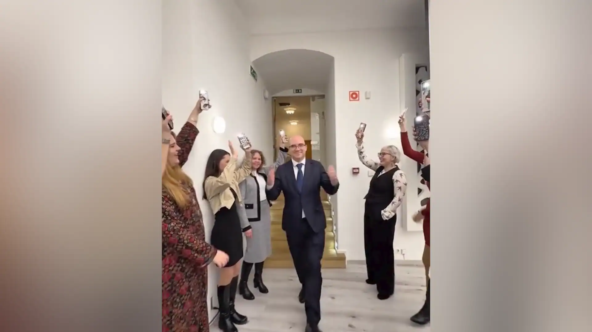 Boldog ember köszönti társait, miközben mindenki fényképeket készít.