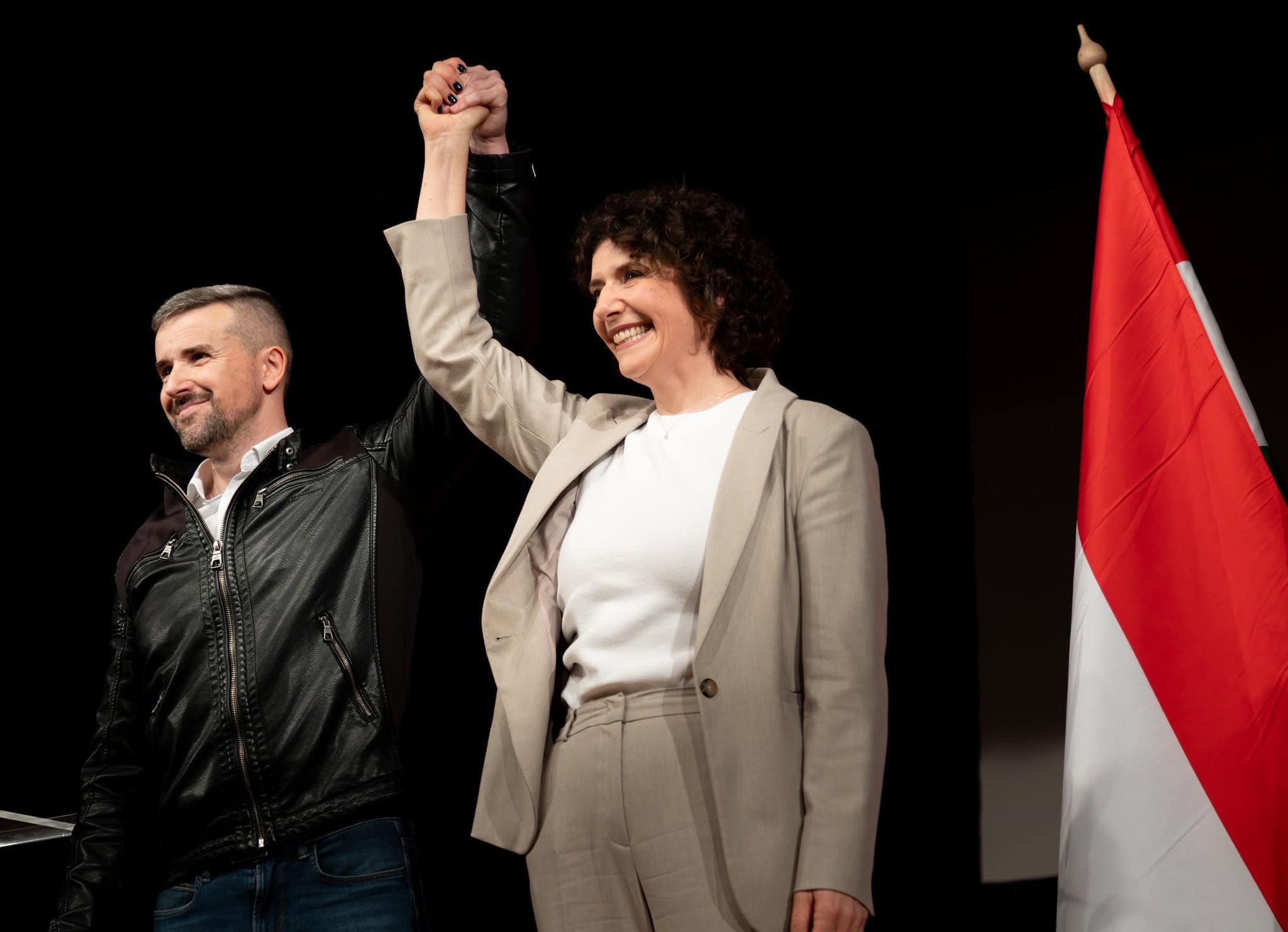 Magyar politikusok ünnepelnek kampánygyőzelmet, és magyar zászló látható a háttérben.