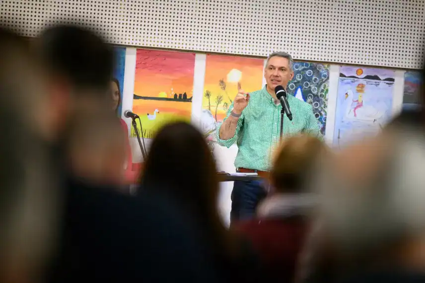 Vágott kép egy férfiról, aki beszél egy mikrofonhoz egy művészeti kiállításon.