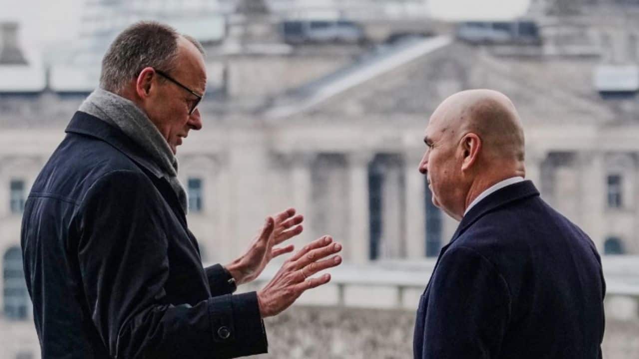 Politikusok beszélgetnek az utcán, háttérben történelmi épületek.