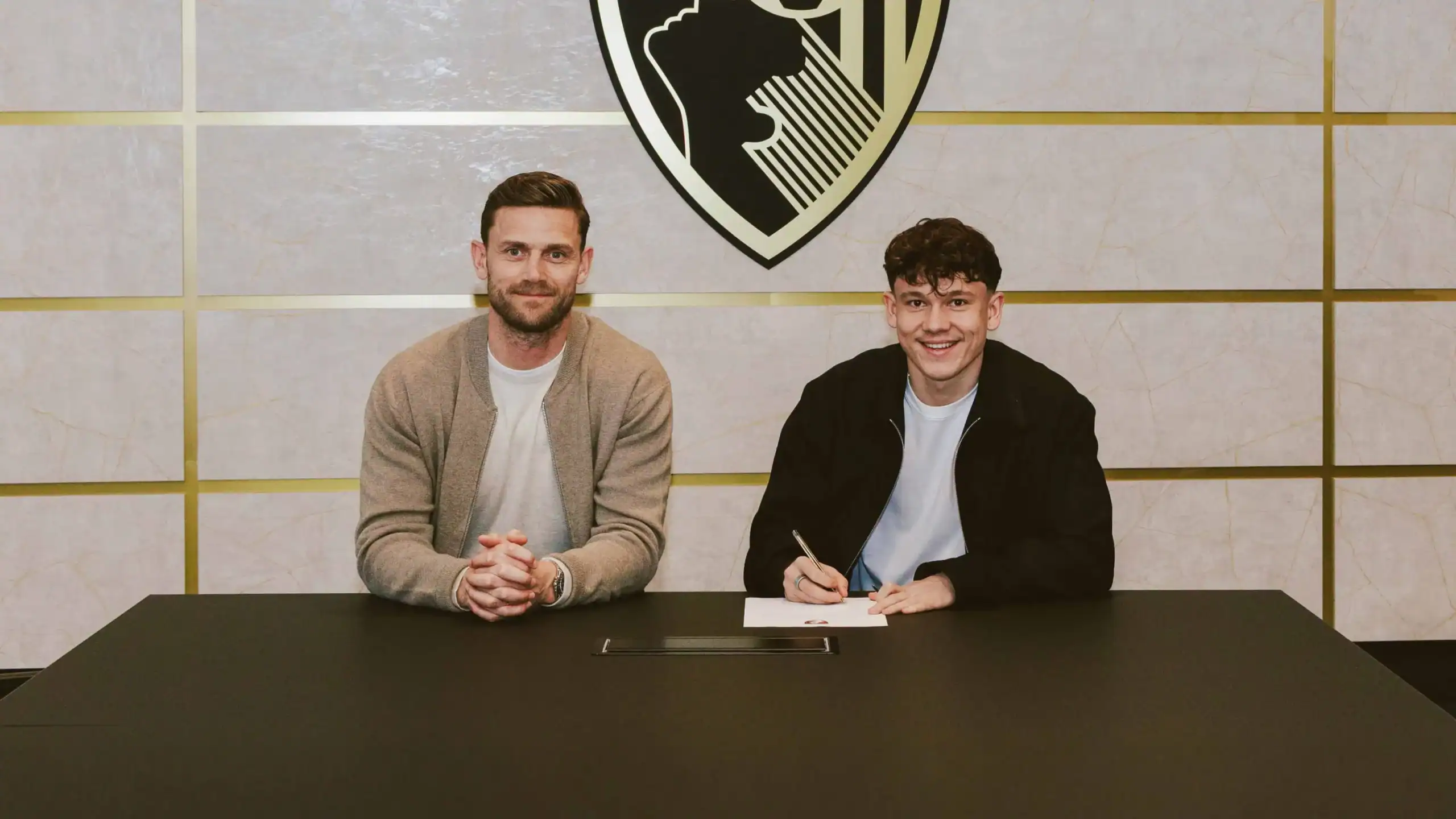 Szerzők aláírása: fiatal labdarúgó aláír szerződést klubjánál a magyar szurkolók örömére.