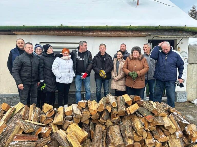 Csoportkép közösen fákat rakodnak a hideg időben.