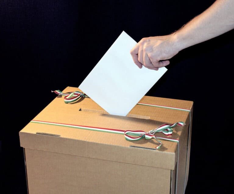Szavazólap bedobása egy szavazóurnába, jelképezve a választási folyamatot.