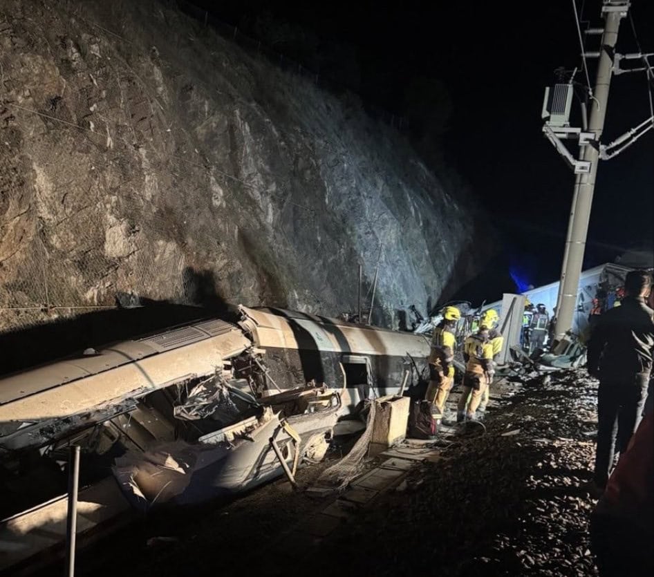 Szerencsétlen vonatbaleset éjjel, súlyosan megrongálva a vágány és az elektromos berendezések. Tűzoltók és mentők dolgoznak a helyszínen.