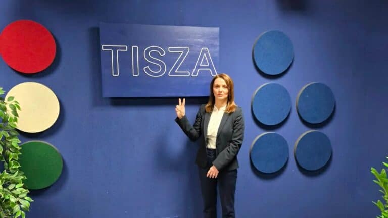 Álló női beszélgetőpartner a Tisza konferencián, háttérben a Tisza felirat és kék díszítőelemek.