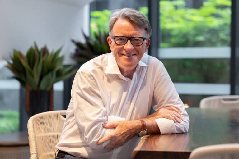 Örömmel mosolyog, üzletasszonyos környezetben, modern iroda előtt.