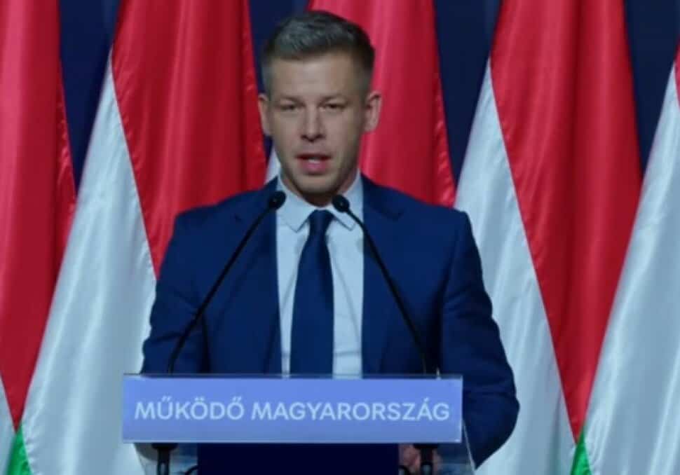 Magyar Péter beszédet tart egy politikai eseményen, háttérben magyar zászlók.