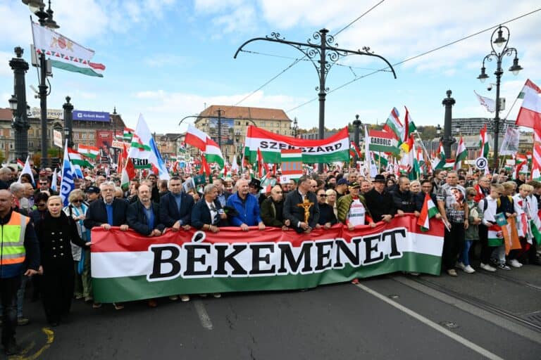 Békemenet felvonulás a március 15-i nemzeti ünnepen, sok résztvevő és nemzeti zászlók a fővárosi utc.