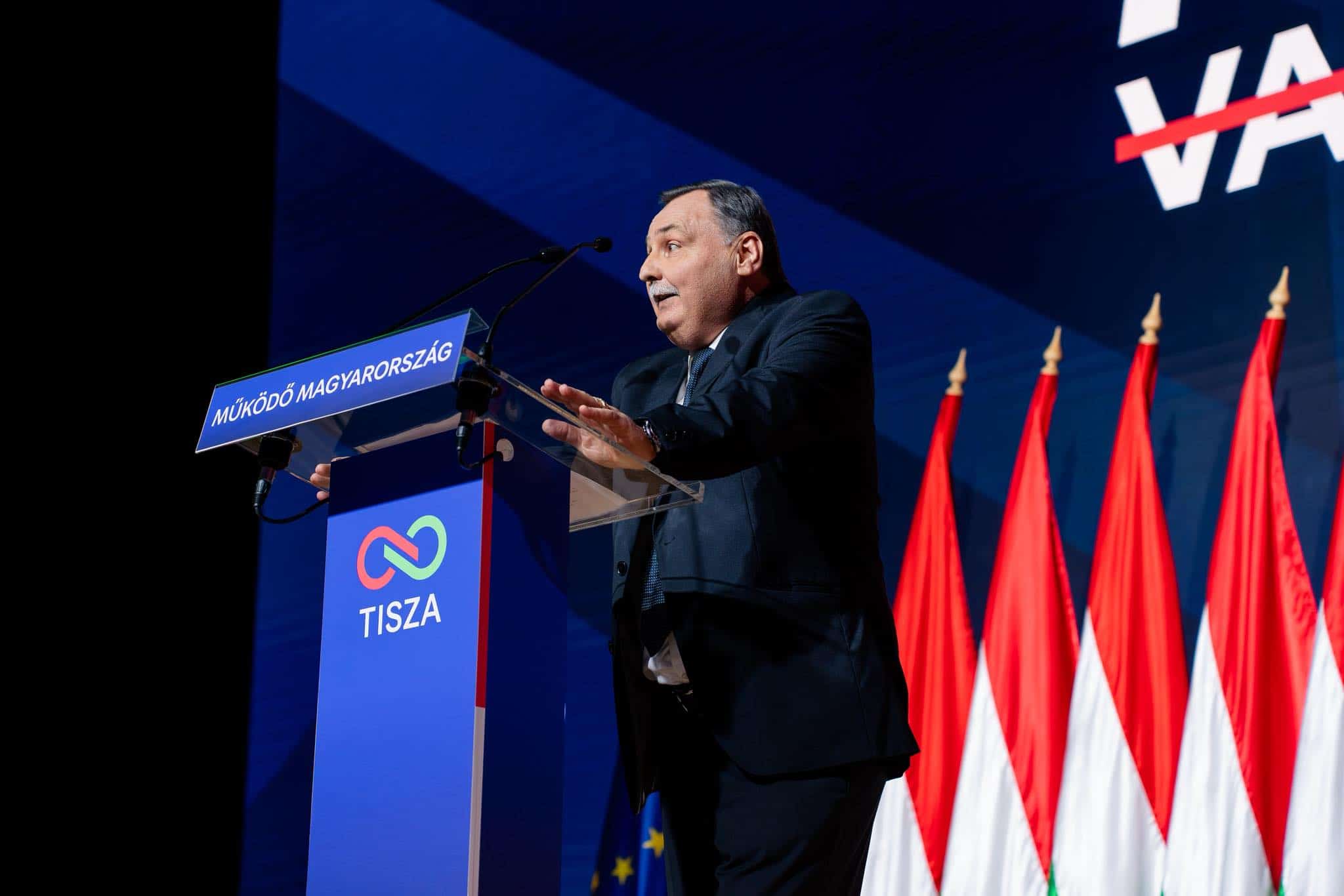 Magyar Péter a Tisza konferencián, háttérben magyar és európai zászlók.