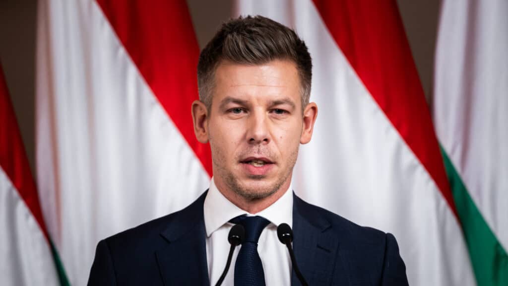 Orbán Viktor évértékelő beszéd közben, háttérben magyar zászlók.