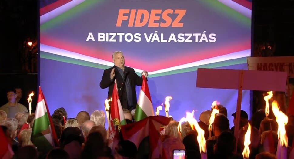 Fidesz politikus beszél a kampánygyűlésen Nagykanizsán, háttérben a "FIDESZ A BIZTOS VÁLASZTÁS" feli.