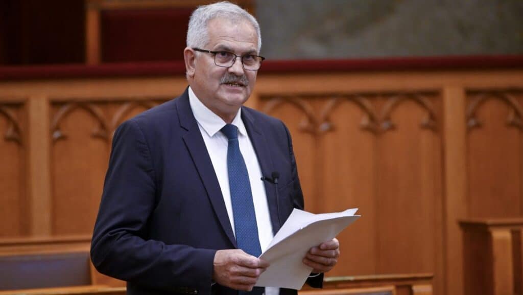 Politikus a parlamenti ülésen, aki dokumentumokat tart a kezében.