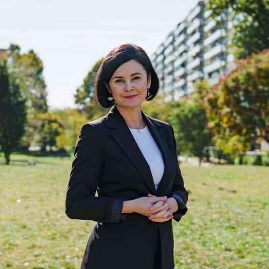 Kunhalmi Ágnes a nyilvános parkban, háttérben lakóépületek.