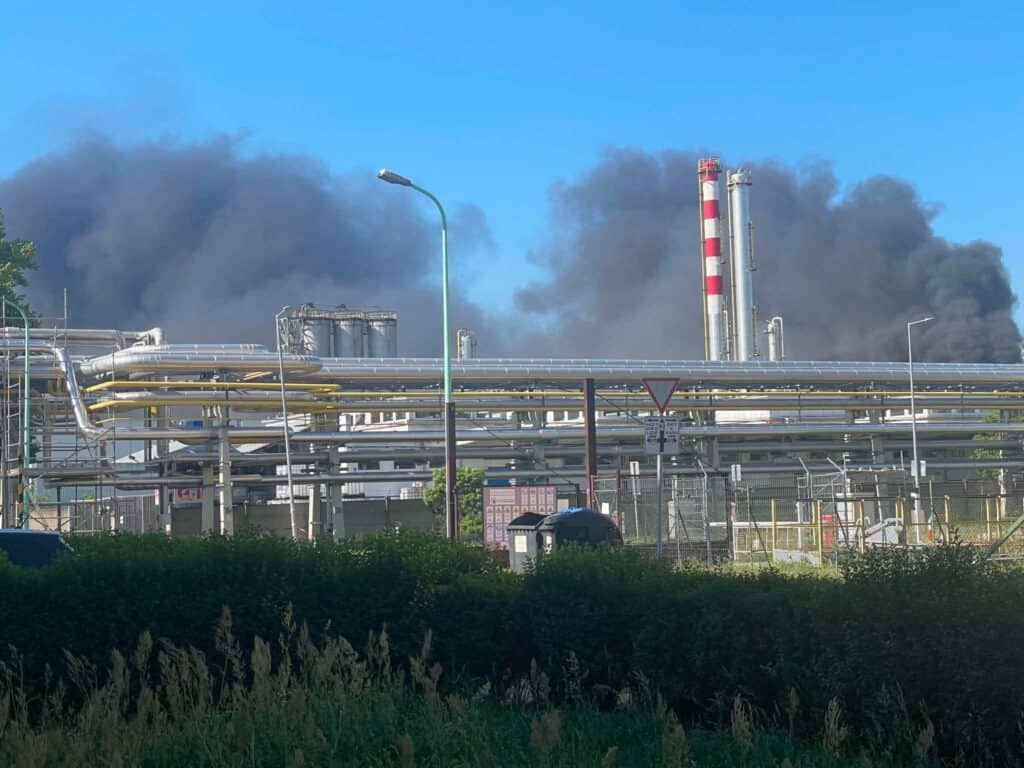 Ipari üzem és kémények, sűrű fekete füstöt kibocsátva a tiszta kék ég felé.