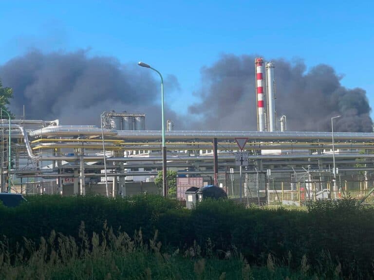 Ipari üzem és kémények, sűrű fekete füstöt kibocsátva a tiszta kék ég felé.