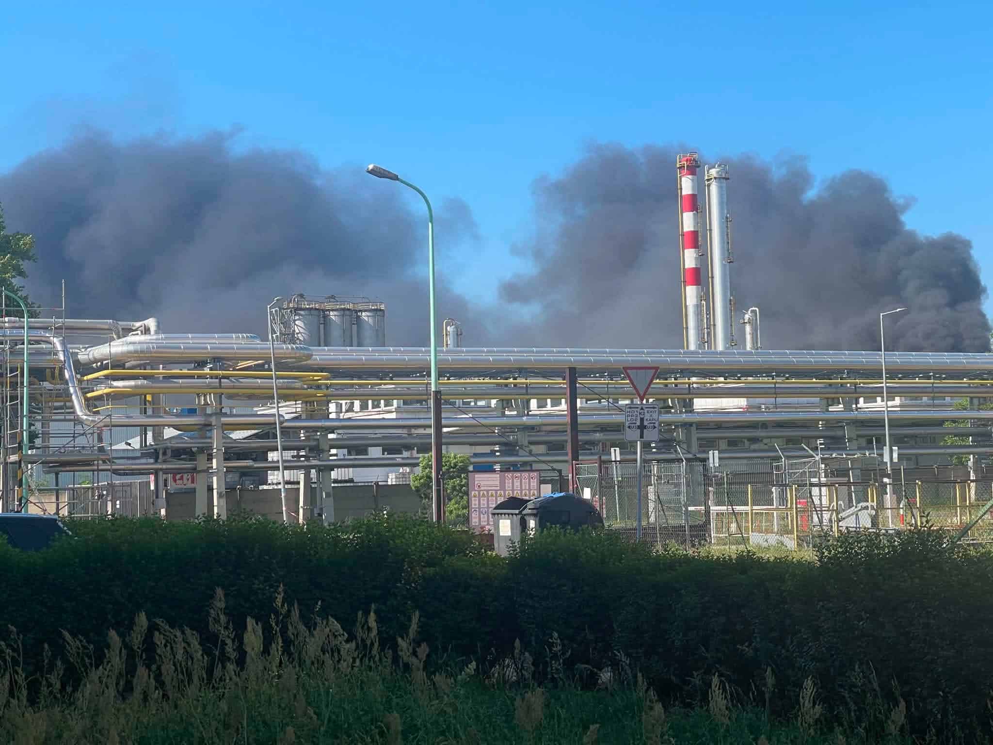 Ipari üzem és kémények, sűrű fekete füstöt kibocsátva a tiszta kék ég felé.