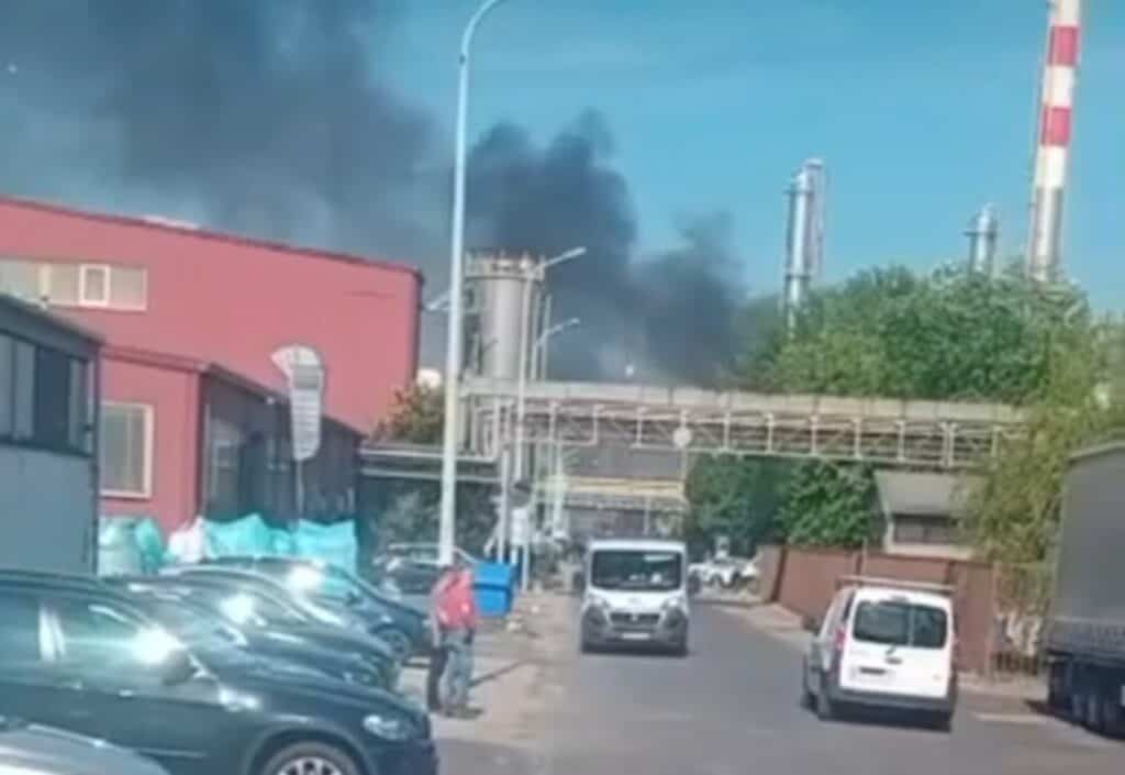 Füst és tűz az ipari területen, több jármű és épület látható a képen.