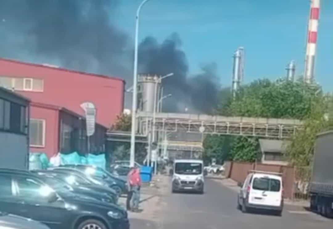 Füst és tűz az ipari területen, több jármű és épület látható a képen.