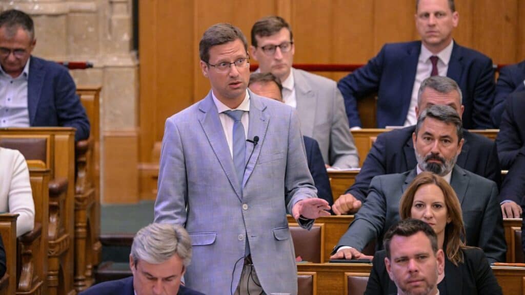 Magyar politikus beszél a parlamentben, több képviselő hallgatja figyelmesen.