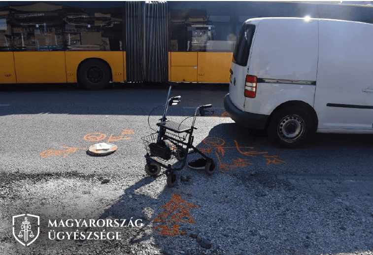 A kép egy elhagyott elektromos rollerrel és egy járókerettel az úton, a háttérben egy sárga busz par.