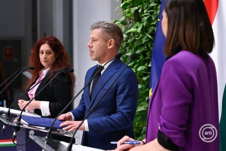 Magyar politikusok sajtótájékoztatón, háttérben nemzeti és uniós zászlók.