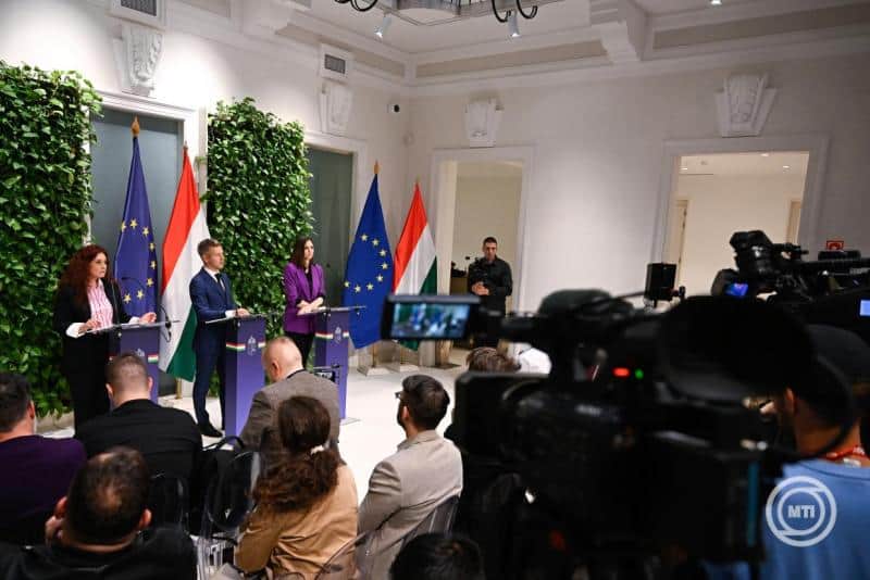 EU és magyar zászlók a háttérben, sajtótájékoztató a konferenciateremben.