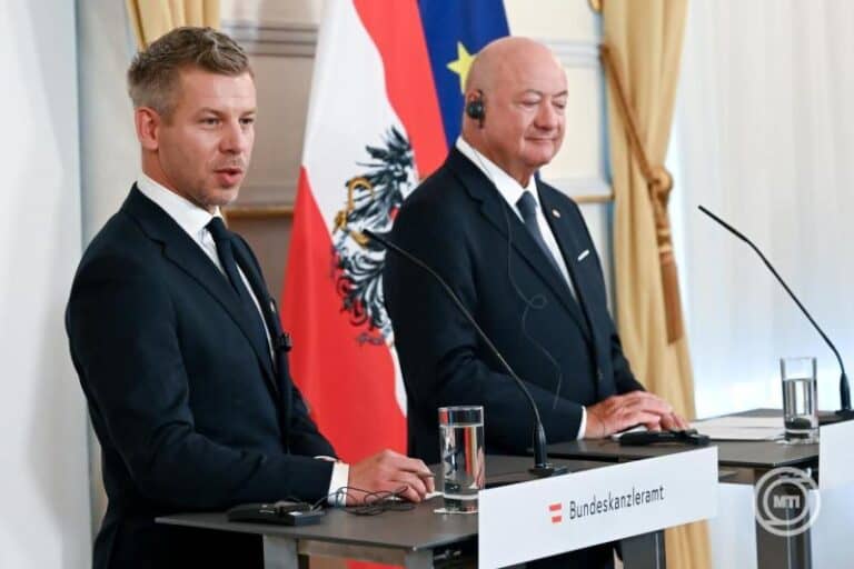 Két férfi beszél egy sajtótájékoztatón, háttérben az osztrák és az EU zászlók.