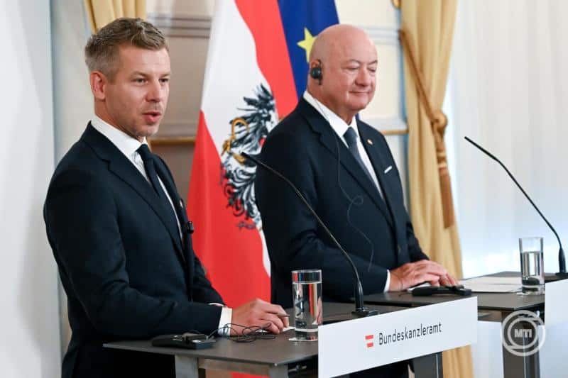 Két férfi beszél egy sajtótájékoztatón, háttérben az osztrák és az EU zászlók.