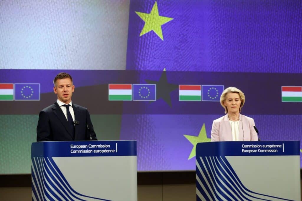 Európai Bizottság sajtótájékoztatója, két beszélő a színpadon.