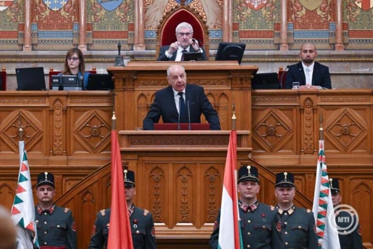 Magyar miniszterelnök beszédet mond a parlamentben, katonák állnak sorfal előtt.