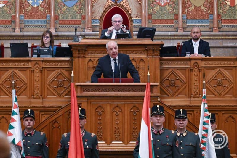 Magyar miniszterelnök beszédet mond a parlamentben, katonák állnak sorfal előtt.