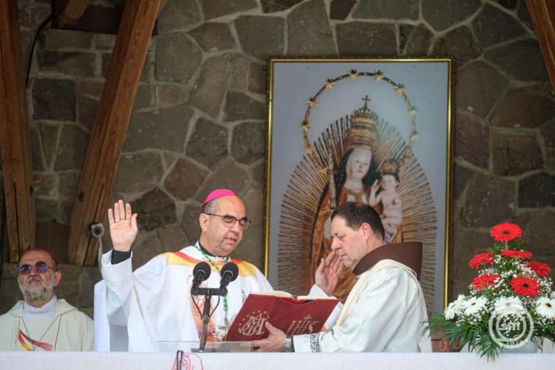 Magyar katolikus papok szentmisét tartanak templomban, háttérben vallási kép.