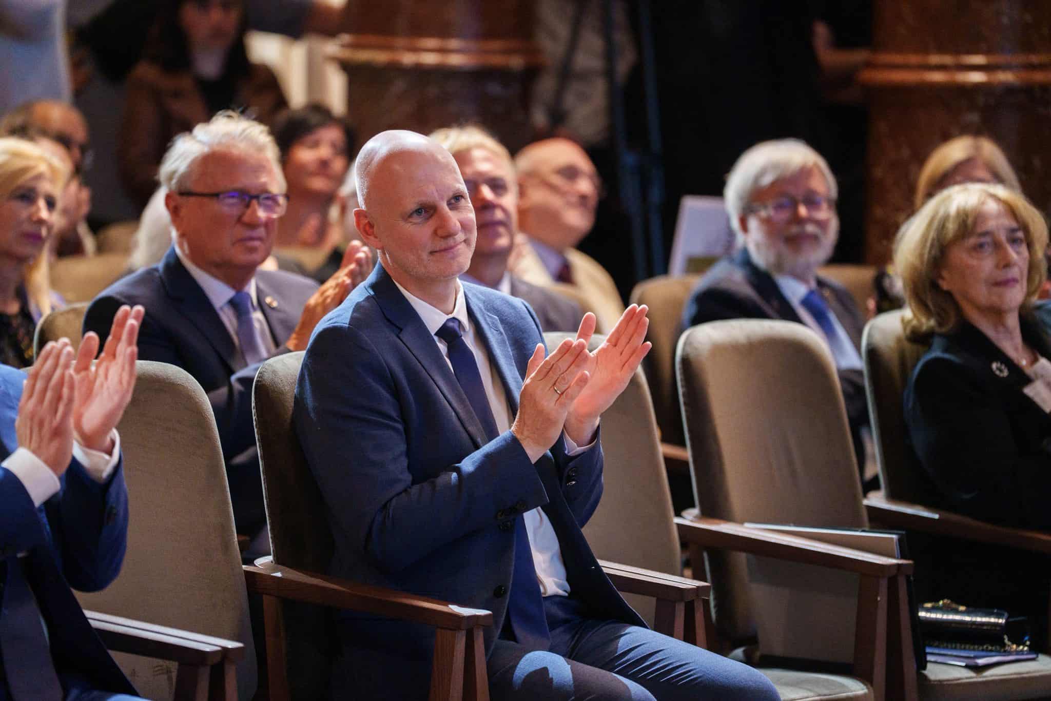 Üzletemberek és szakemberek figyelnek egy konferencián, figyelmesen hallgatva a beszédet.